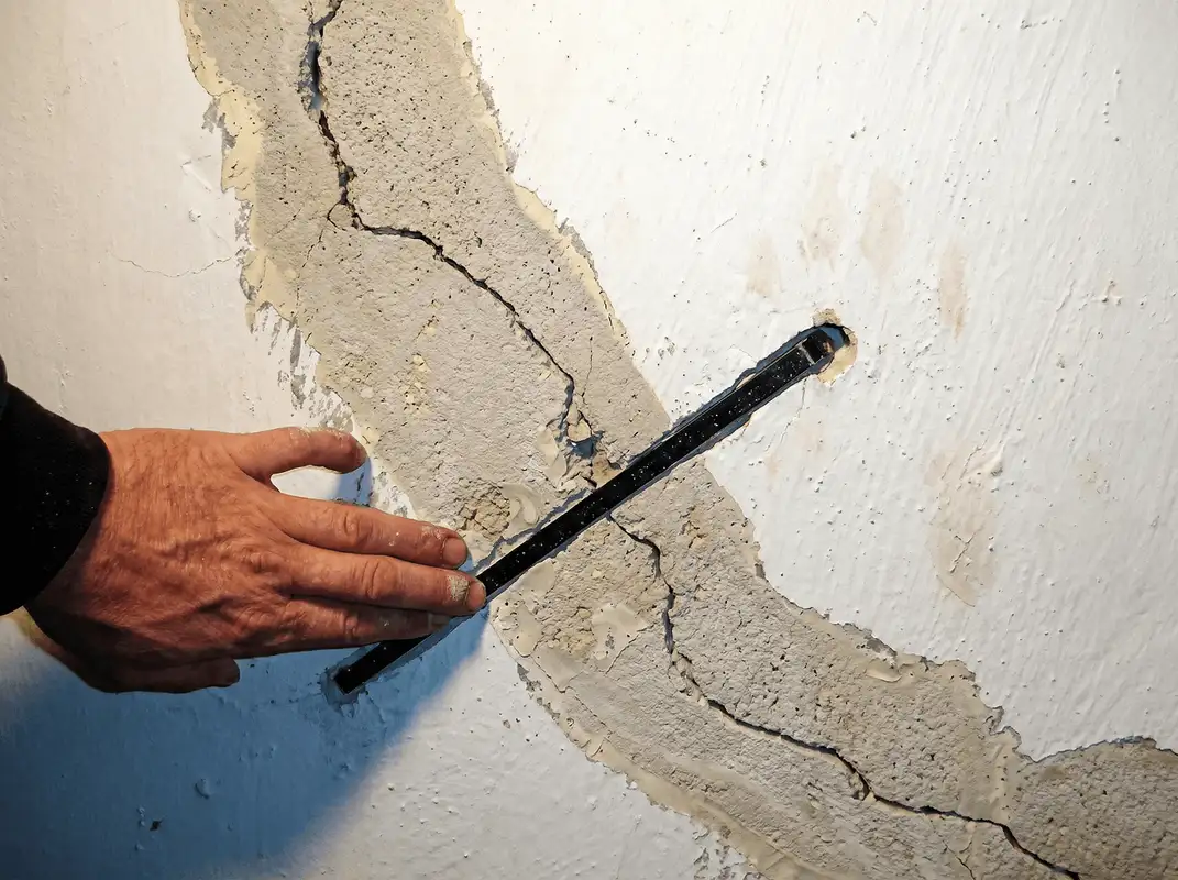A wall with a large crack is being inspected by a professional in Oakland, CA